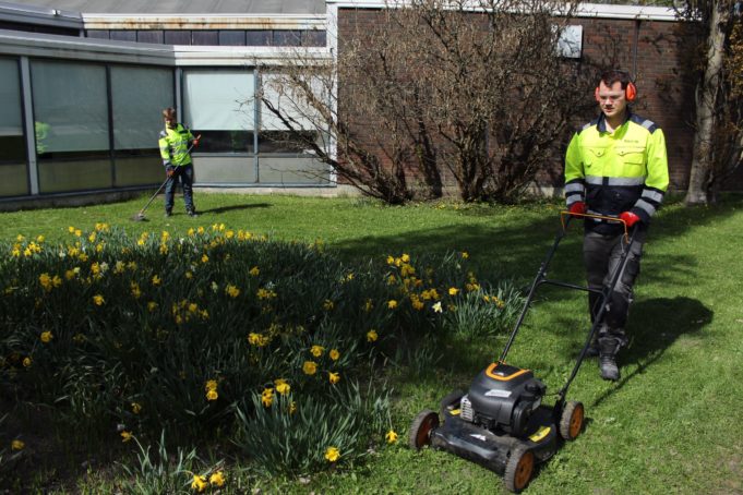 Työpaja Viitakummun nuoria leikkaamassa nurmikkoa ja haravoimassa.