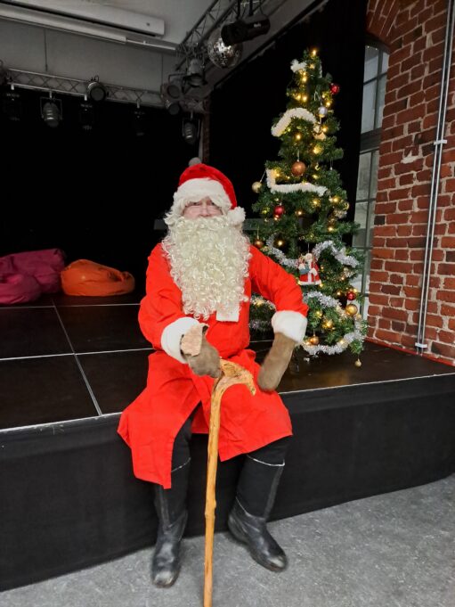 Joulupukki istuu NuortenPaikan esiintymislavan reunalla.